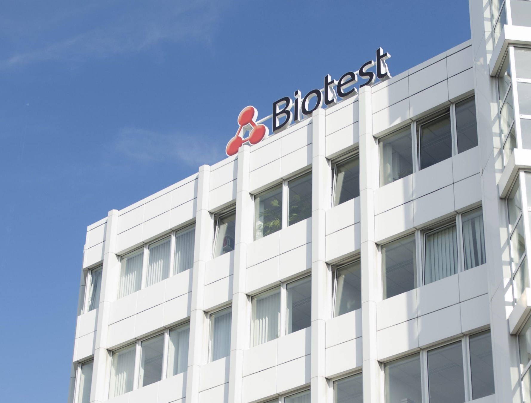 up to data | Biotest office building with company logo and signage against blue sky